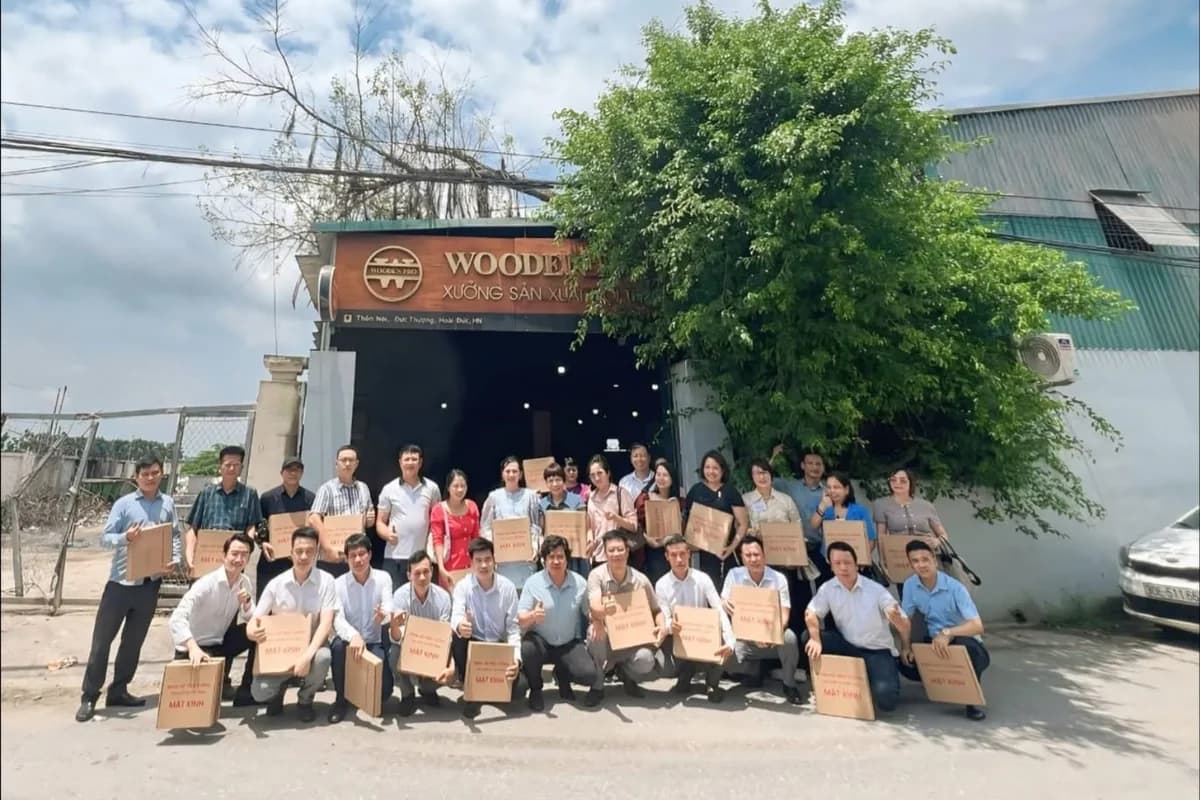 Đoàn Givers cầm sản phẩm gỗ chụp ảnh trước cửa xưởng WoodenPro